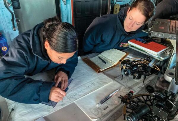 La coauteure, à droite, et l'un de ses quartiers-maîtres à bord de l'USS Essex (LHD-2) tracent une route dans la timonerie du navire. Afin de s'assurer que les officiers de quart sur le pont puissent maintenir un tracé précis et continu sur papier, la capitaine de corvette Stanton a exigé des exercices de traçage pendant les deux traversées transocéaniques (de San Diego à Guam, puis du Japon à Oahu). Photo Marine américaine (Walter O'Donnell)